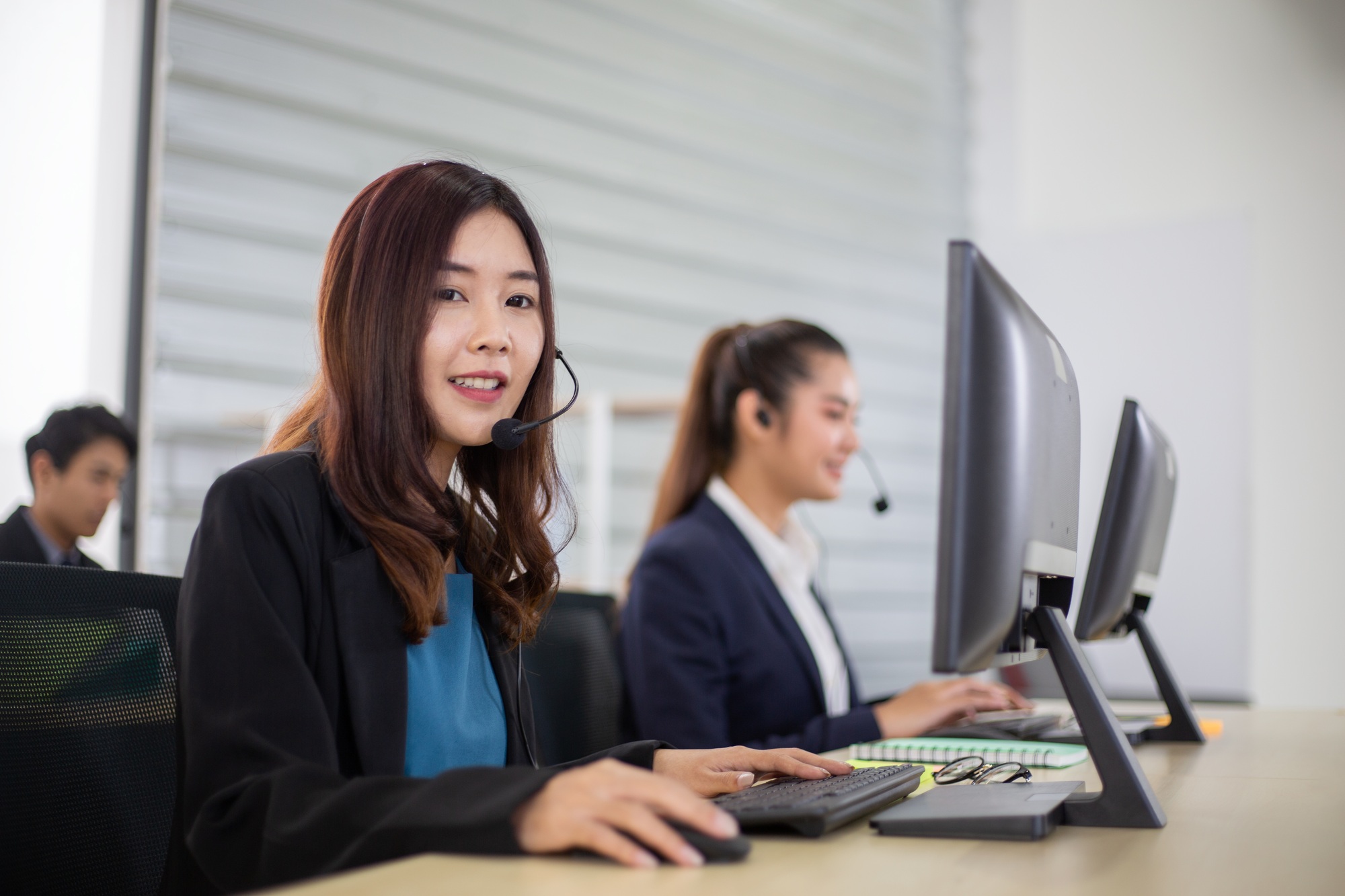 Asian call center corporate team with headphone talking to customer in the office
