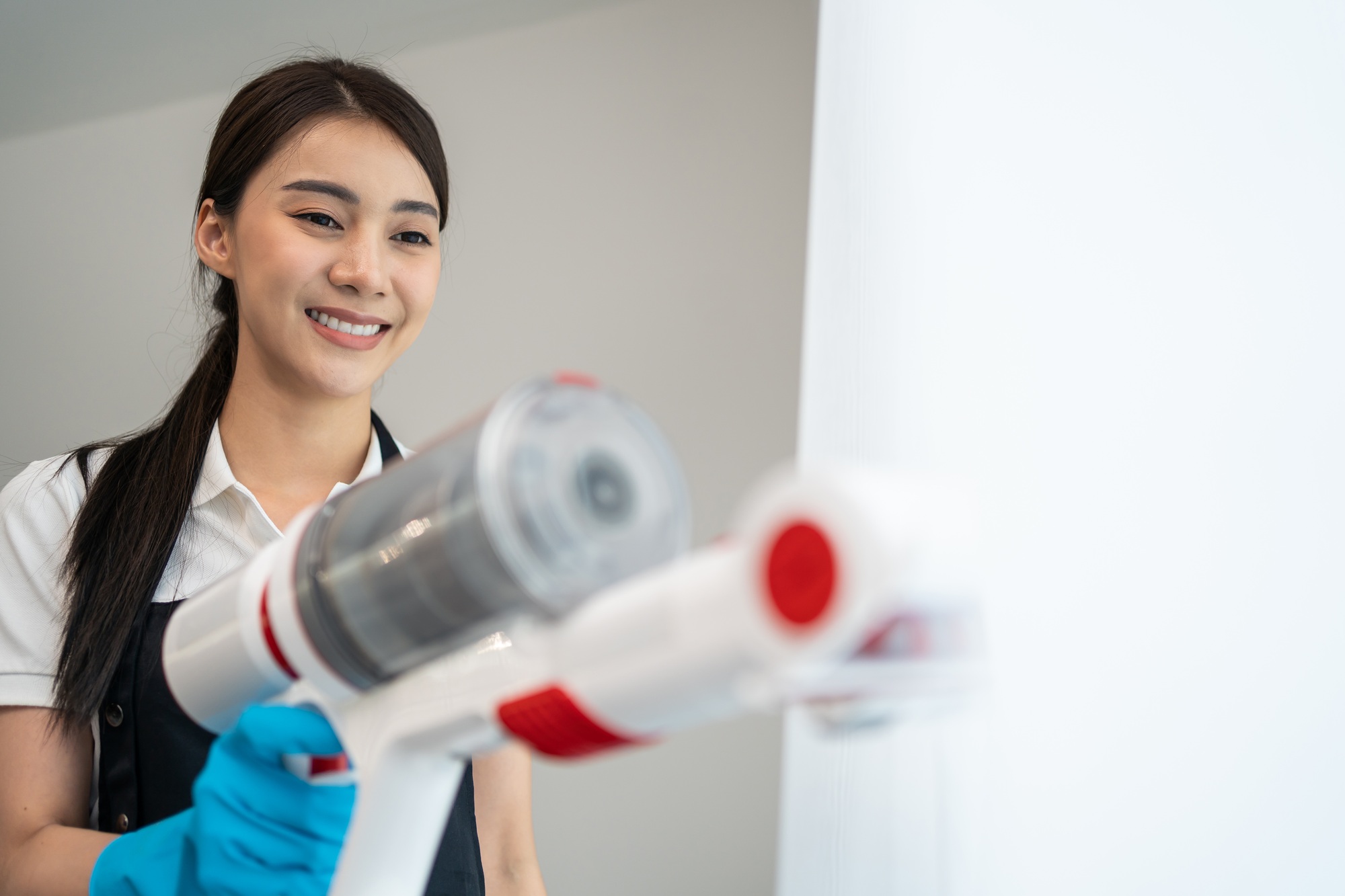 Asian cleaning service woman worker cleaning in living room at home.