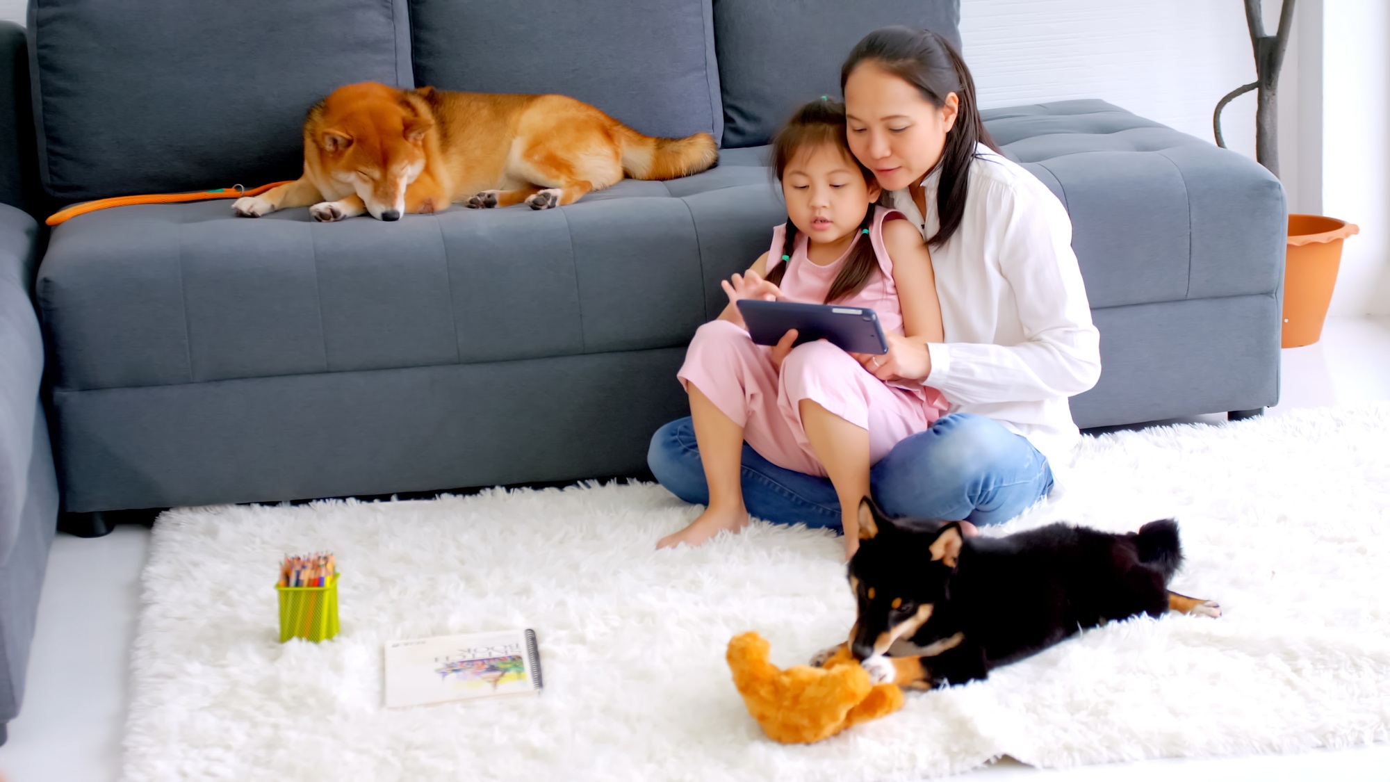 Mother and little daughter with their dog spending time together at home.